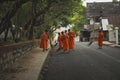 luangprabang lao-july19,2023 : group of wat xiangthong novice sweaping dry leaves on street beside the temple on early morning , Royalty Free Stock Photo