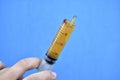 Lubricants in a syringe in your hand on a blue background Royalty Free Stock Photo