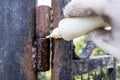 lubricating of rusty gate hinge with oil outdoors