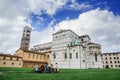 LUCCA, ITALY - OCTOBER 5, 2017: Group of tourists with bicycles near romanesque facade and bell tower of St. Martin Cathedral. It