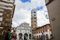 LUCCA, ITALY - OCTOBER 5, 2017: People walk the square in front of romanesque facade and bell tower of St. Martin Cathedral. It