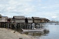 Small fishing boat anchored beside the over water stilt Bajau shanty houses. Long shot