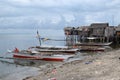 Small fishing boat anchored beside the over water stilt Bajau shanty houses. Long shot