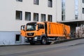 LUCERNE, SWITZERLAND - January 2021: orange cargo garbage truck driving through city streets, collecting garbage from bins, waste