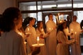 Lucia parade with singing girls and boys in white dresses holding candles. Traditional celebration of the suffering of saint