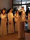 Lucia parade with singing girls and boys in white dresses holding candles. Traditional celebration of the suffering of saint