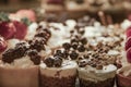 Lucious and delicious tiny deserts on display topped with berries and whipped cream and nuts and chocolate - selective focus and