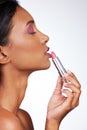 Lucious lips. Studio shot of an attractive young woman applying lipstick against a grey background.