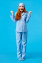 Luck, happiness and victory concept. Vertical full-length studio shot cheerful triumphing redhead female in nightwear