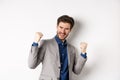 Lucky businessman winning money prize, say yes and smiling excited, make fist pump sign to celebrate victory, triumphing Royalty Free Stock Photo