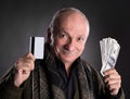 Lucky elderly man holding dollar bills and credit card