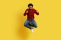 Lucky happy indian guy jumping and gesturing on yellow