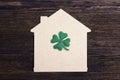 Lucky home symbol with four-leaf clover on wooden background. Royalty Free Stock Photo