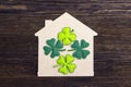 Lucky home symbol with four-leaf clover on wooden background. Royalty Free Stock Photo