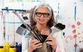 Lucky, proud portrait of an older mature smiling woman, artist, in her fifties with grey hair and glasses, and many big Royalty Free Stock Photo