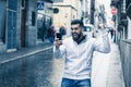 Lucky young man with fist up celebrates victory holding cellphone on street