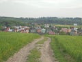 Ludgerovice, Czech - 05 16 2015: Panoramic view on a village with multicolored houses behind a field with a dirt road in the Royalty Free Stock Photo