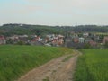 Ludgerovice, Czech - 05 16 2015:Panoramic view on a village with multicolored houses behind a field with a dirt road in the right Royalty Free Stock Photo