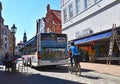 Medieval town of Lueneburg. You see the facades of bricks and small shops. A public bus tortures itself through the narrow alley