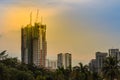 Luffing jib tower cranes on the top of under construction building with sunset sky background. Silhouette of the building Royalty Free Stock Photo