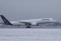 Lufthansa Airbus plane taxiing on runway, snow