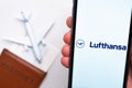 Lufthansa airline company app or logo displayed on a mobile phone with passport, boarding pass and plane on the Royalty Free Stock Photo