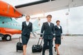 With luggage. Aircraft crew in work uniform is together outdoors near plane Royalty Free Stock Photo