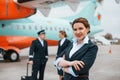 With luggage. Aircraft crew in work uniform is together outdoors near plane Royalty Free Stock Photo