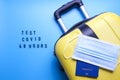 Luggage bag and mask on a blue background. Word test for covid 48 hours. Travel only with a covid test