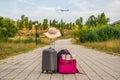 Luggage in the middle of the street with an airplane in the background.