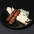 Lula kebab with greens on a black plate on a black background Royalty Free Stock Photo