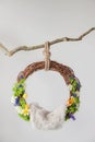 Lullaby of grapevine ring with spring flowers for newborn children hanging on a branch on a white background