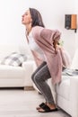 Lumbago, or low back pain suddnly hits a woman trying to stand up from a couch Royalty Free Stock Photo