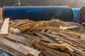 Lumber scattered in front of industrial pipes