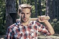 Lumberjack carries axe on shoulder. Deforestation. Handsome man with axe. Lumberjack in the woods with an ax. Royalty Free Stock Photo