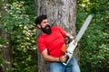 Lumberjack with chainsaw on forest background. Man doing mans job. Lumberjack with chainsaw in his hands. Lumberjack