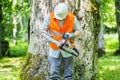 Lumberjack checking chainsaw near tree