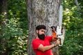 Lumberjack concept. Professional lumberjack holding chainsaw in the forest. Man doing mans job. Handsome young man with