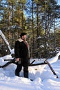 lumberjack in forest with an axe. Brutal man with beard in winter snow-covered forest. Man is dressed in warm sheepskin coat,