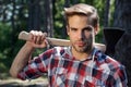 Lumberjack handsome man on serious face with axe outdoor. Close up portrait of young guy woodcutter hold ax. Mens power