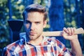 Lumberjack man carries axe on shoulder. Woodcutter with axe in the summer forest. Lumberjack holding the axe. Royalty Free Stock Photo