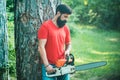 Lumberjack in the woods with chainsaw axe. Handsome young man with axe near forest. Lumberjack with chainsaw on forest Royalty Free Stock Photo