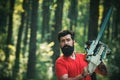 Lumberjack in the woods with chainsaw axe. Professional lumberjack holding chainsaw in the forest. Woodworkers