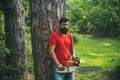 Lumberjack worker with chainsaw in the forest. Handsome young man with axe near forest. Stylish young man posing like Royalty Free Stock Photo