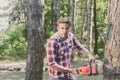 Lumberjack worker with chainsaw in the forest. Professional lumberjack holding chainsaw in the forest. Lumberjack