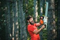 Lumberjack worker walking in the forest with chainsaw. Professional lumberjack holding chainsaw in the forest. Illegal