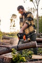 Lumberman in protective goggles sawing with chainsaw tree trunk in summer forest. Royalty Free Stock Photo