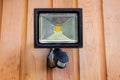 Lumineux flood sensor light fixed to a wooden wall outside of a house