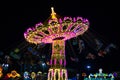 Luminous carousel turntables spin with people in the evening. Fun for kids and adults in an amusement park Royalty Free Stock Photo