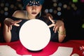 Luminous crystal ball and cards on magnificent fortune telling table with mysterious beautiful woman fortune teller in black dress Royalty Free Stock Photo